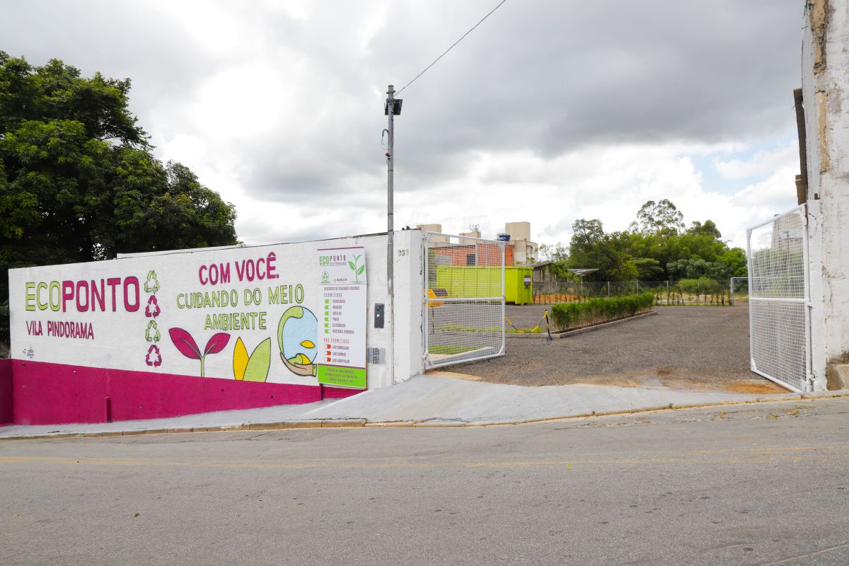 Fachada da entrada do Ecoponto Vila Pindorama em Barueri, com portão aberto e muro ilustrado para descarte correto de resíduos.